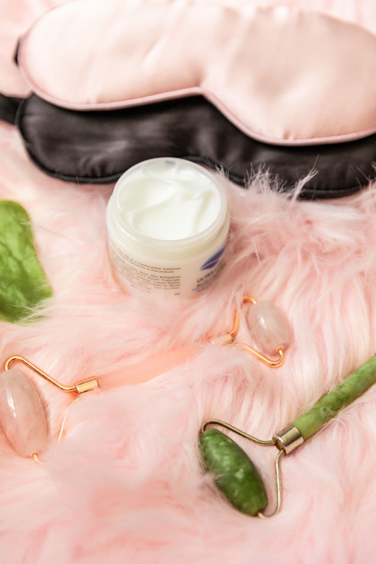 Facial rollers, moisturizer, and silk eye masks arranged for a self-care routine